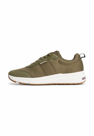 Botte de sport vert olive avec des panneaux en mesh, bout arrondi et semelle intermédiaire blanche. Caractérisée par un talon texturé et une semelle extérieure beige avec des accents en rayures.