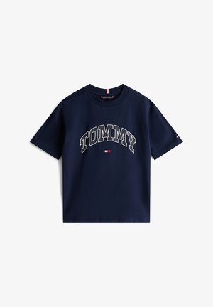 Camiseta de algodón azul marino con el gran texto "TOMMY" en color crema, y un pequeño logotipo en rojo y blanco en el frente y en la manga.