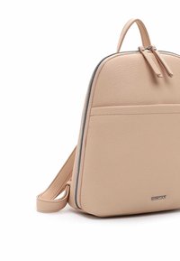 Sac à dos en cuir beige avec dessus arrondi, fermeture éclair argentée visible, poche avant, poignée supérieure et bretelles réglables.