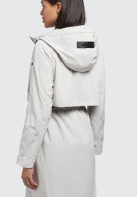Lichtgrijze cropped jas met een capuchon, voorzien van een zwart etiket op de achterkant, met een gladde textuur en een elastische tailleband.