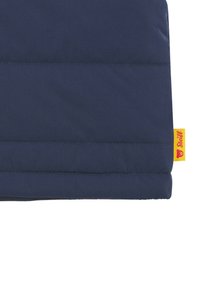 Tessuto imbottito blu navy con righe verticali, caratterizzato da un'etichetta gialla con un logo di orso. La cucitura è scura e ordinata.