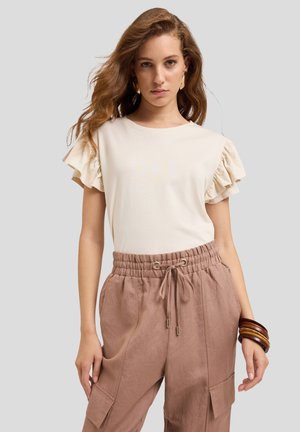 Light beige short-sleeve t-shirt with ruffled sleeves paired with light brown pants featuring an elastic waistband and side pockets.