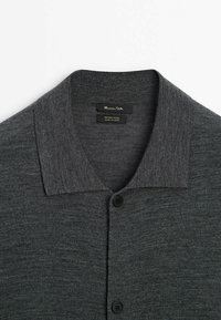 Cardigan en laine mérinos gris foncé à boutons avec col, présentant une texture de tricot lisse et deux boutons noirs visibles.