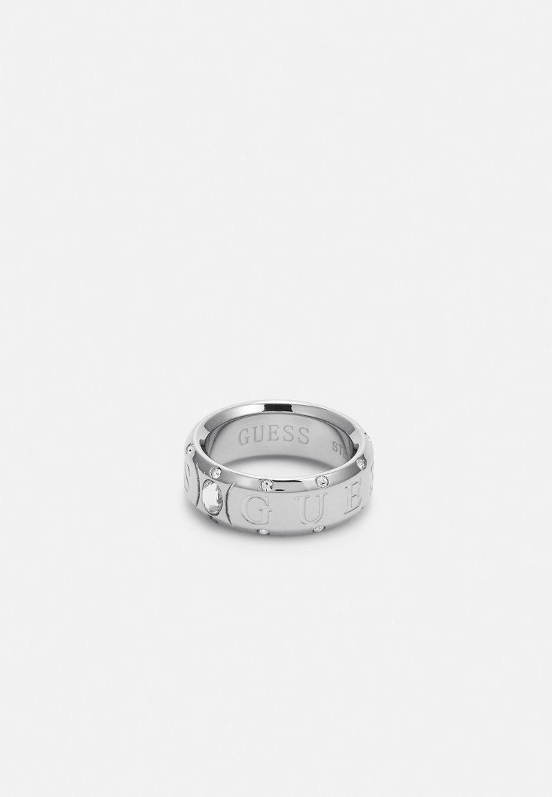 Silberner Metallring, graviert mit "GUESS," mit kleinen klaren Edelsteinen, die rund um den Ring gefasst sind. Glattes, abgerundetes Design mit polierter Oberfläche.