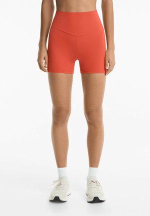 Pantaloni corti rossi a vita alta realizzati in materiale elasticizzato con una texture liscia. Lunghezza a metà coscia, con una cintura larga per il massimo comfort.