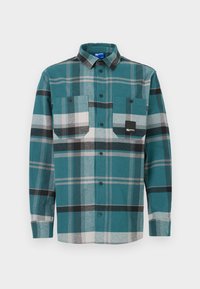 Károvaná košile v barvách modrozelené, černé a šedé. Obsahuje dvě náprsní kapsy, límec na knoflíky a dlouhé rukávy. Vyrobena z měkké, texturované tkaniny.