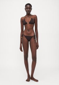 Brown bikini set featuring a triangle top with decorative beads and matching low-rise bottoms with side ties. Smooth, lightweight fabric.