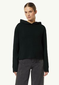 Czarna bluza z kapturem o luźnym kroju, miękkiej fakturze i długich rękawach, w połączeniu z szarymi dżinsami z srebrnymi akcentami.