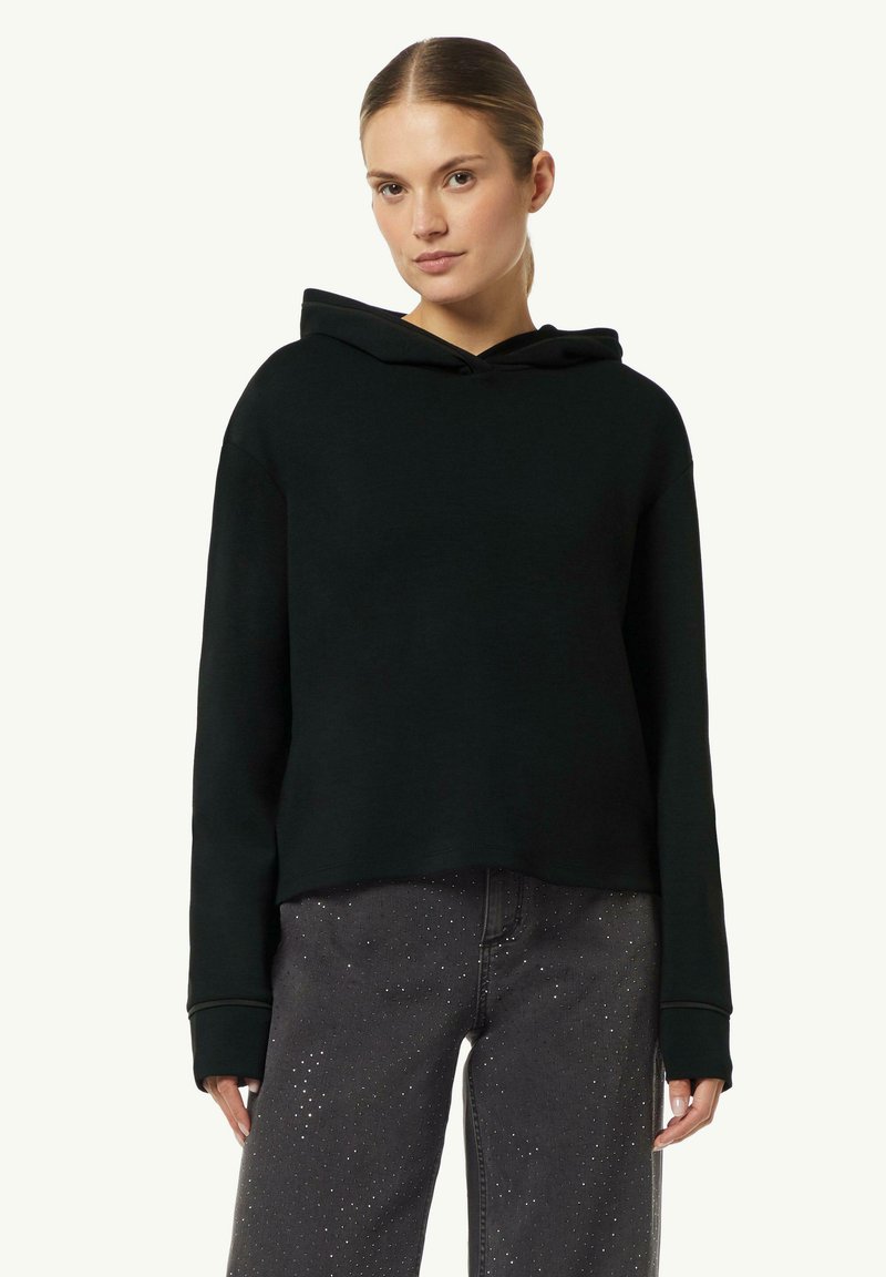 Czarna bluza z kapturem o luźnym kroju, miękkiej fakturze i długich rękawach, w połączeniu z szarymi dżinsami z srebrnymi akcentami.