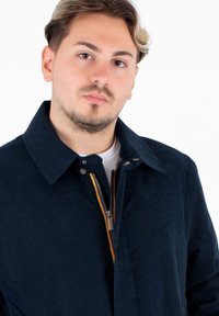 Giacca di velluto a coste blu navy con un ampio colletto, chiusura frontale con zip e un accento arcobaleno, e tessuto testurizzato.