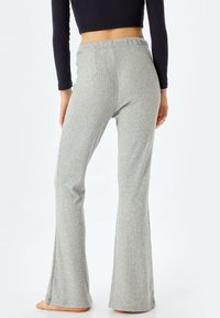 Grijze ribgebreide broek met een flare, voorzien van een elastische tailleband en een zachte textuur, met een subtiele stretch voor comfort en gemakkelijke beweging.