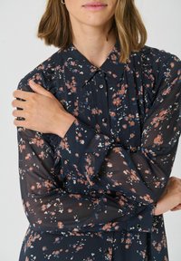 Rochie florală bleumarin cu țesătură transparentă, având flori mici portocalii și albastre, cu guler și detalii cu nasturi pe mâneci și la placket.