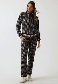 Survêtement à motifs noir et blanc composé d'une veste zippée avec des détails côtelés et d'un pantalon assorti. Confectionné dans un tissu doux et léger.