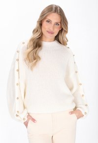 Pulover alb din tricot, cu guler înalt, mâneci oversize și nasturi decorativi aurii pe părți. Textură moale, croială lejeră.