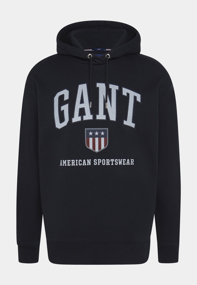 Sweat à capuche noir avec "GANT" en grandes lettres blanches, un blason avec des étoiles et des rayures, et le texte "American Sportswear" sur le devant.