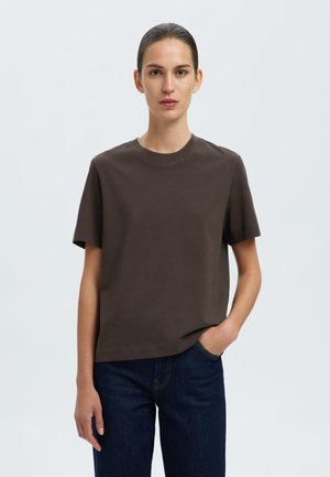 T-shirt de algodão castanho com mangas curtas, decote redondo, corte descontraído e textura suave, combinado com jeans azul-escuro.