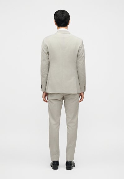 Ανοιχτό γκρι κοστούμι, εφαρμοστή γραμμή, σακάκι με γιακά notch, ασορτί παντελόνια, λείο ύφασμα, σετάρισμα με μαύρα επίσημα παπούτσια.