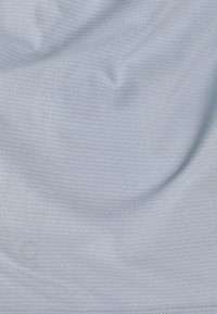 Ljusblått tyg med en slät textur och subtilt ribbat mönster, med lätta rynkor och en sydd fåll längs nedre kanten.