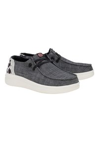 Zapatillas de lona negras y grises con suela de goma blanca, patrón texturizado, cordones negros y un acento decorativo en el talón. Presenta el logotipo en la lengüeta.