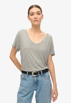 Graues V-Ausschnitt-T-Shirt aus weichem Stoff, mit kurzen Ärmeln und lockerer Passform, kombiniert mit hellblauen Jeans und einem schwarzen Gürtel mit einer silbernen Schnalle.