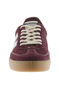 Sneaker in suede borgogna con accenti bianchi ai lati, punta rotonda e suola in gomma beige. I lacci sono di colore crema e presentano dettagli di cucitura.