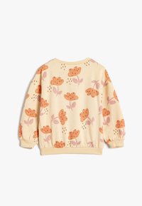 Sudadera crema con mangas abullonadas, con un patrón floral en naranja y rosa. Puños y dobladillo acanalados para un ajuste recogido.