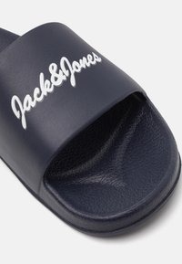 Sandale de piscine marine en matériau synthétique texturé avec une large bride. Logo "Jack & Jones" en blanc contrastant sur la bride.
