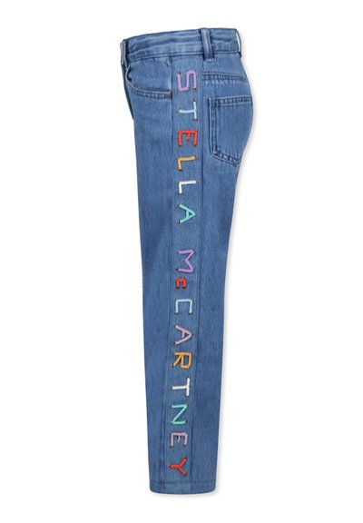 Jeans in denim di colore azzurro chiaro con ricami colorati che compongono la scritta "STELLA McCARTNEY" lungo il lato esterno della gamba sinistra.