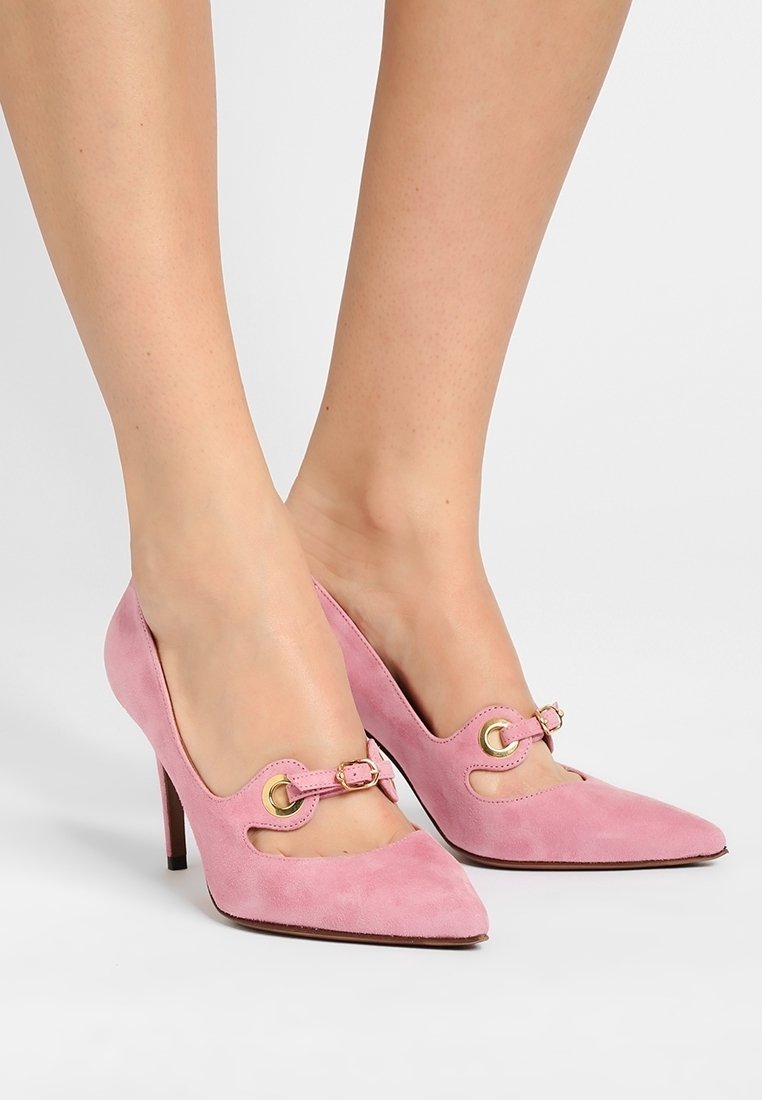 Chaussures à talons hauts en daim rose avec un bout pointu et des découpes, ornées d'accents en métal doré et d'un fin talon aiguille.