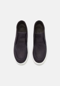 Marinblå slip-on skor gjorda av slät läder med rund tå och vit gummisula. Minimalistisk design, ingen synlig hårdvara eller mönster.