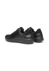 Black sneakers with a smooth leather upper, textured fabric accents, round toe, and a thick rubber sole, featuring lace closure and minimalistic design.