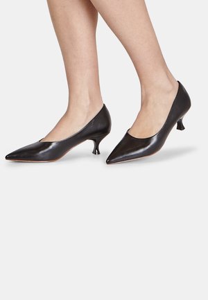 Black leather pumps with a pointed toe and low kitten heel. Smooth texture and simple design, featuring a subtle cutout along the edge.