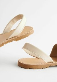 Sandali in pelle beige con due cinturini larghi e suola in gomma naturale. La soletta presenta una semplice cucitura lungo il bordo.