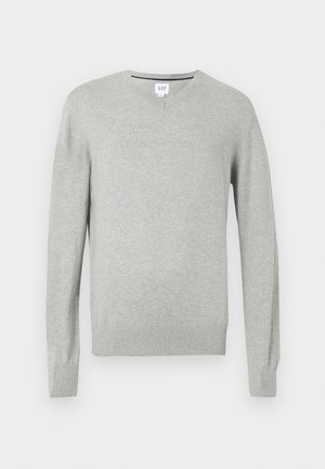 Gaiši pelēks džemperis, ar V veida kaklu, garām piedurknēm, ribota apkakle un apakša, mīksta tekstūra. Zīmola uzlīme atrodas uz kakla.