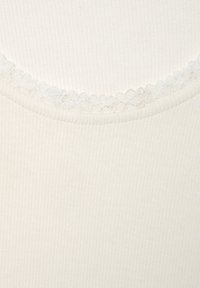 Crèmegekleurde tanktop met ribbelstructuur, voorzien van een scalloped kantafwerking langs de ronde halslijn. Zachte stof, casual fit.