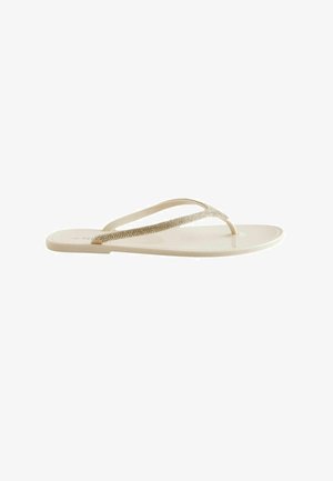 Beežid madalad plätud läikiva tallaga ja õhukeste, rhinestone'idega kaunistatud rihmadega vabaaja kandmiseks.