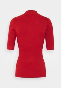 Haut rouge à manches courtes en tricot côtelé avec un col montant et une silhouette ajustée, vu de dos sur fond blanc.