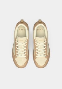 Bežiniai ir šviesiai rudi sportbačiai, pagaminti iš odos ir tinklelio medžiagų, turintys apvalų priekį, raištelius ir subtilias perforacijas ant noselės.