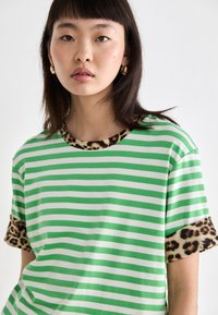 Groene en witte gestreepte t-shirt met luipaardprintaccenten op de mouwen en de halslijn, gemaakt van zachte, lichte stof.