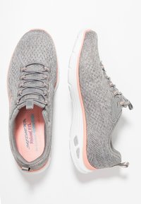 Grå sportskor med en stickad ovandel, matchande snören och en vit sula med rosa detaljer. Slip-on-stil med vadderad krage och texturerade detaljer.