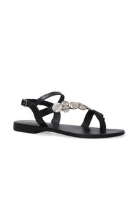 Zwarte leren platte sandalen met kruisbanden en een decoratieve metalen embellissement met een textuur. Eenvoudig en minimalistisch ontwerp.