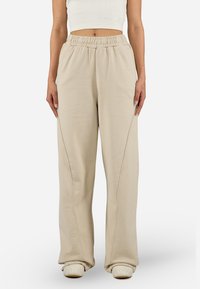 Lys beige joggebukser med elastisk midje og sidesømmer, som har en avslappet passform. Laget av mykt stoff med en jevn tekstur.
