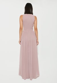 Robe maxi en mauve clair, sans manches avec un corsage ajusté et une taille froncée, jupe plissée fluide. Texture douce et lisse. Fermeture éclair au dos.