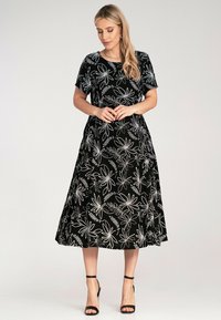 Black floral print dress featuring short sleeves, a round neckline, and a flowing A-line skirt, with white embroidered leaf patterns.