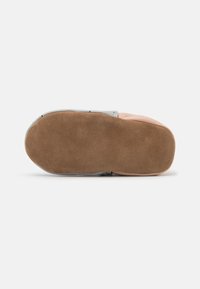 Schuhsohle mit einem braunen Wildlederfinish, gewellter Zehenform und grauem Gummirand. Flache und flexible Form, geeignet für den Innenbereich.