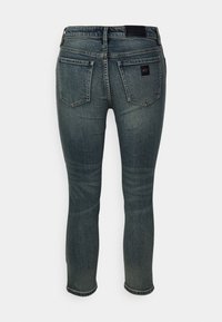 Tmavě modré slim-fit džíny s vybledlými detaily, dvěma zadními kapsami a černou koženou značkovou nášivkou na pase a kapse.