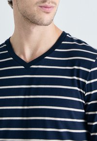 Dunkelblaues V-Neck T-Shirt mit horizontalen weißen Streifen. Hergestellt aus einem weichen, glatten Stoff, verfügt es über ein tailliertes Design, das den Ausschnitt betont.