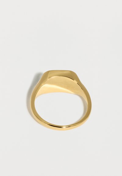 Λείο, γυαλιστερό χρυσό δαχτυλίδι σημιόσχημο με επίπεδη, χωρίς εγχάρακτα οβάλ επιφάνεια, εμφανισμένο από πάνω σε απλό ανοιχτό γκρι φόντο.