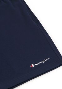 Marineblaue Sportshorts aus glattem Material; mit Champion-Logo in Weiß und Rot auf der unteren linken Seite. Schlichtes Design ohne Muster.