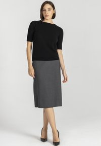 Czarny, krótki rękaw, dzianinowy top połączony z szarym ołówkowym spódnicą. Spódnica ma gładką fakturę i długość do kolan. Czarne szpilki.